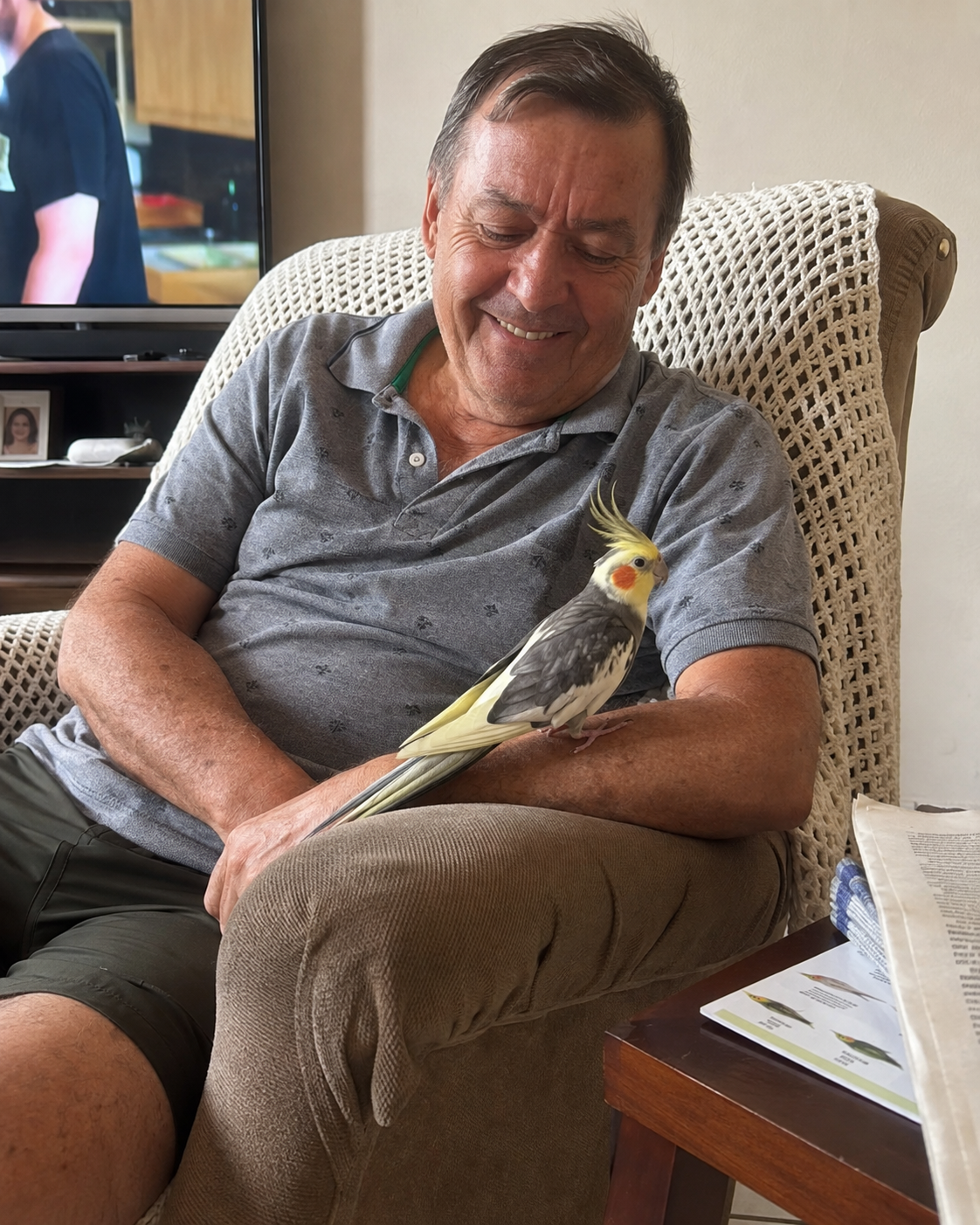 Tutor sorrindo com a calopsita pousada no braço